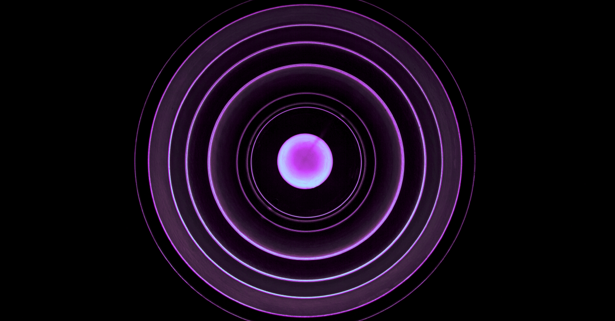 A pink orb has a series of lit up radiating circles flowing out on a dark background.